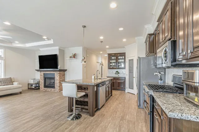 a kitchen with stainless steel appliances granite countertop a stove top oven a sink dishwasher a dining table and chairs with wooden floor