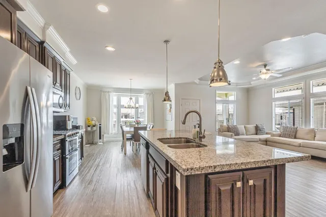 a kitchen with granite countertop a stove a sink dishwasher a refrigerator and wooden floor