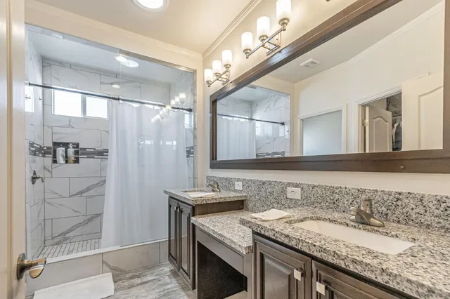 a bathroom with a granite countertop sink a mirror and a shower