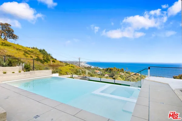 a large kitchen with stainless steel appliances a large counter top a wooden floors and a large window