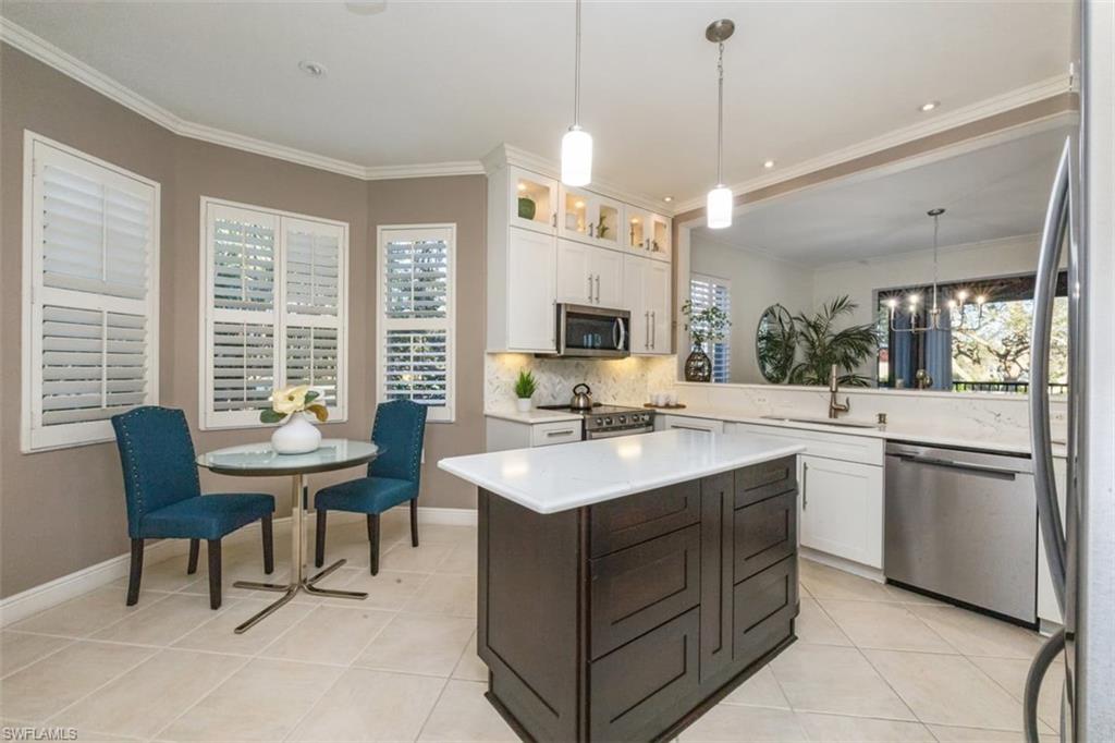 770 Regency Reserve Circle, Unit 1803 Naples, FL 34119 - Photo 10 of 35 Kitchen with stainless steel appliances, decorative light fixtures, white cabinetry, a kitchen island, and decorative backsplash