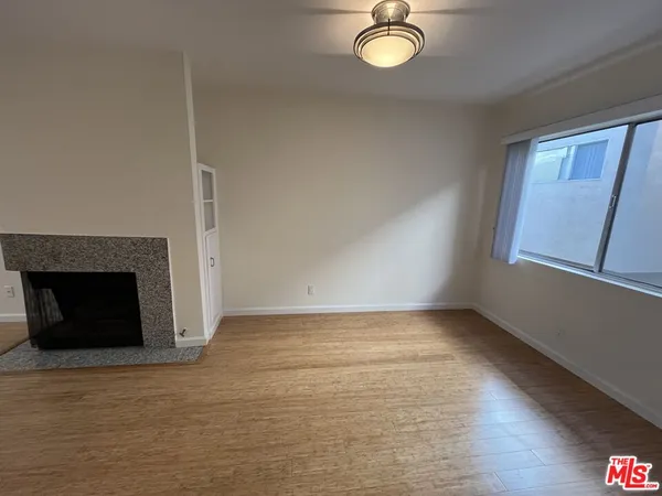 a view of empty room with wooden floor and fireplace