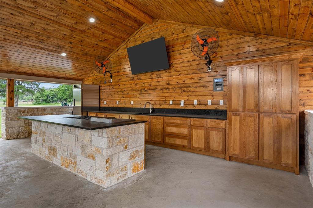 1117 Downsville Road Robinson, TX 76706 - Photo 27 of 40 Covered outdoor living area featuring a stone-clad island, wood-paneled walls and ceiling, extensive cabinetry, and recessed lighting