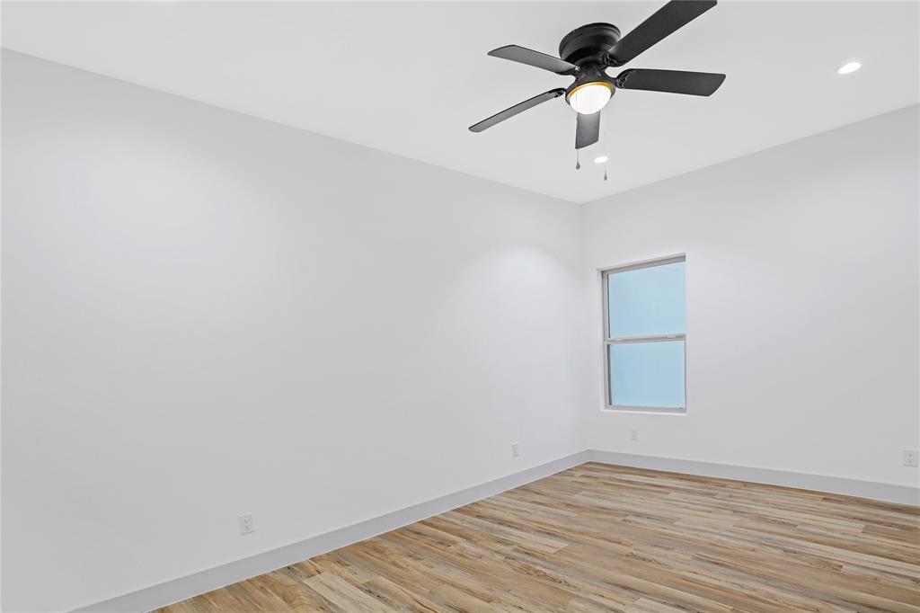 2606 Fordham Road Dallas, TX 75216 - Photo 16 of 19 Bright interior space featuring wood-finish flooring, a contemporary ceiling fan with integrated lighting, recessed lighting, a single window, and clean white baseboards