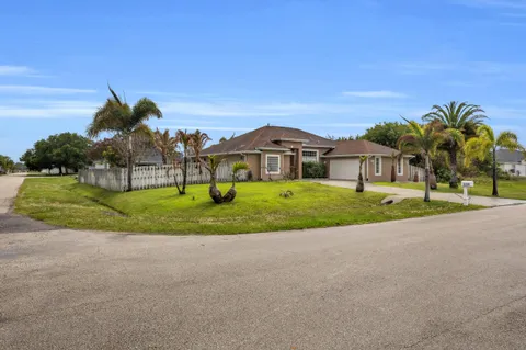 a view of a house with a big yard and palm trees