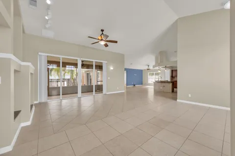 a large white kitchen with a large window cabinets and chandelier