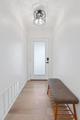 a view of a hallway with wooden floor and a chandelier