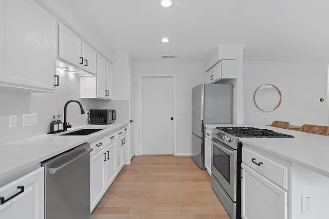 a kitchen with stainless steel appliances granite countertop a sink stove refrigerator and cabinets