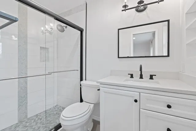 a bathroom with a toilet sink vanity and mirror