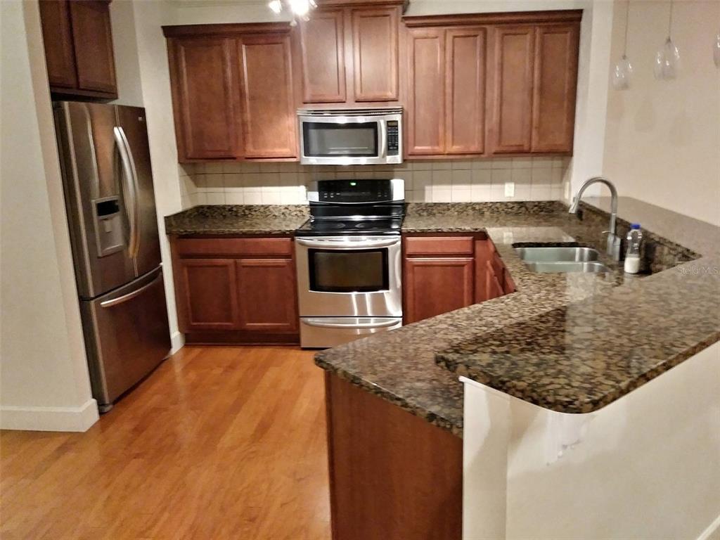 14228 Northwest 23 Lane Gainesville, FL 32606 - Photo 5 of 17 a kitchen with granite countertop stainless steel appliances and wooden cabinets
