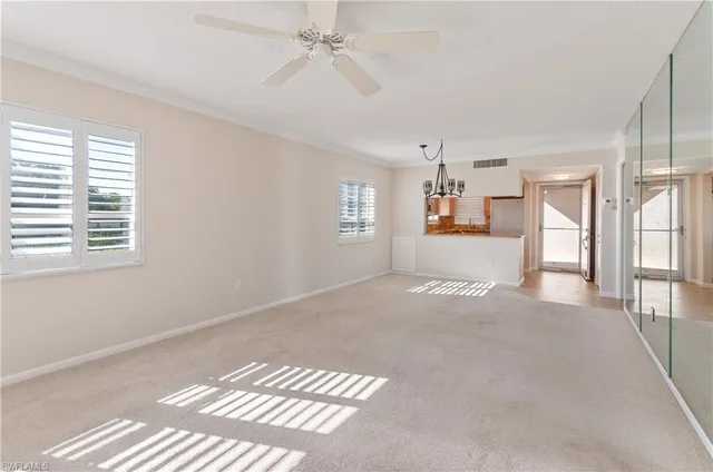 a view of a big room with windows and chandelier fan