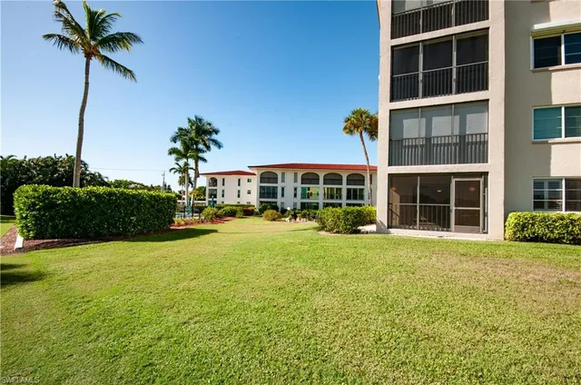 a front view of a house with a yard and potted plants