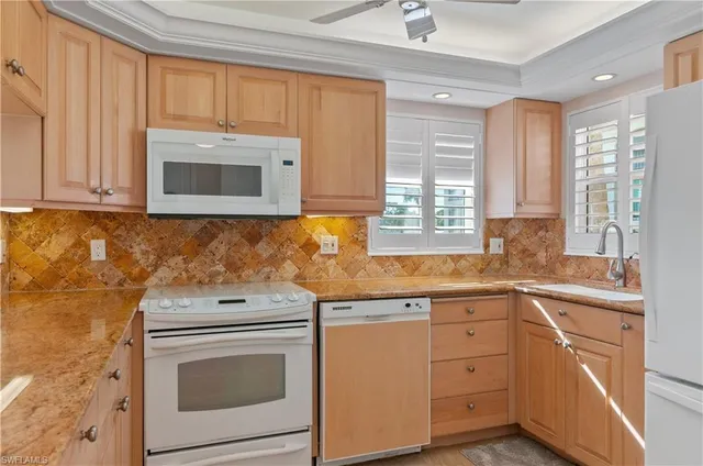 a kitchen with granite countertop white cabinets and white appliances