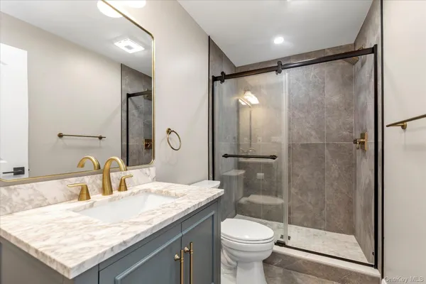 a bathroom with a granite countertop sink toilet and shower