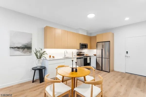 a kitchen with stainless steel appliances kitchen island granite countertop a refrigerator a stove a sink dishwasher a dining table and chairs with wooden floor