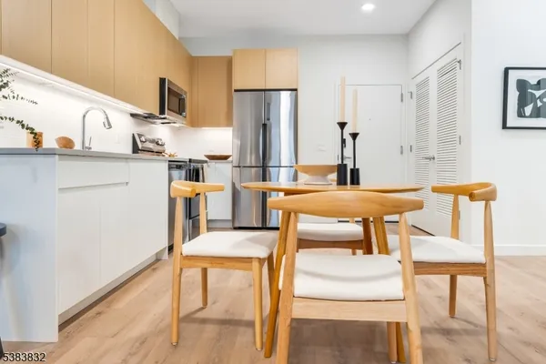 a kitchen with stainless steel appliances kitchen island granite countertop a table chairs and a refrigerator