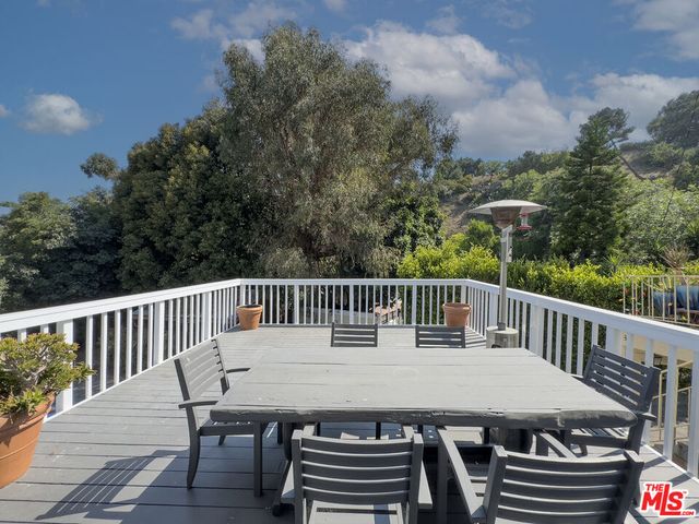 a balcony with wooden floor outdoor seating and trees in the background