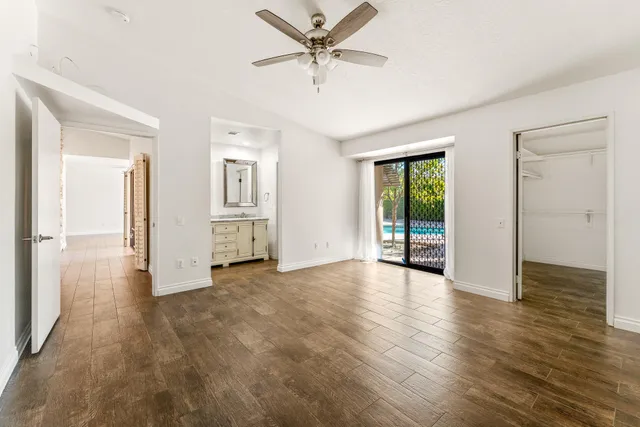 an empty room with wooden floor and a ceiling fan