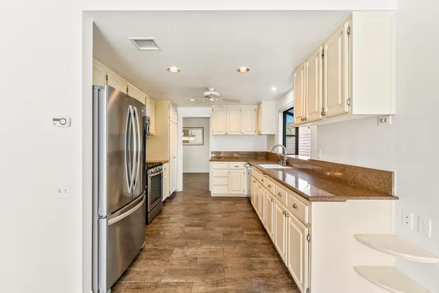 a large kitchen with stainless steel appliances granite countertop a refrigerator and a sink