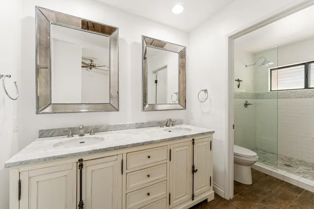 a bathroom with a granite countertop sink toilet and mirror