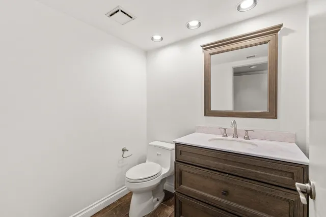 a bathroom with a toilet sink vanity and mirror