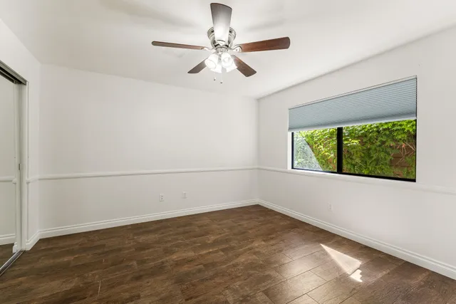 an empty room with a window and a ceiling fan
