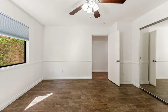 an empty room with a ceiling fan and window