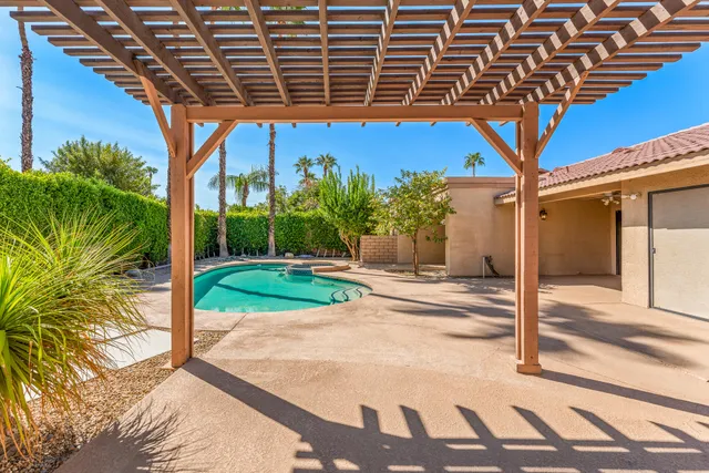 a view of a patio with a table and chairs under an umbrella with a small yard