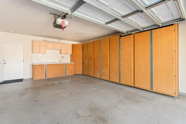 an empty room with chandelier fan and windows