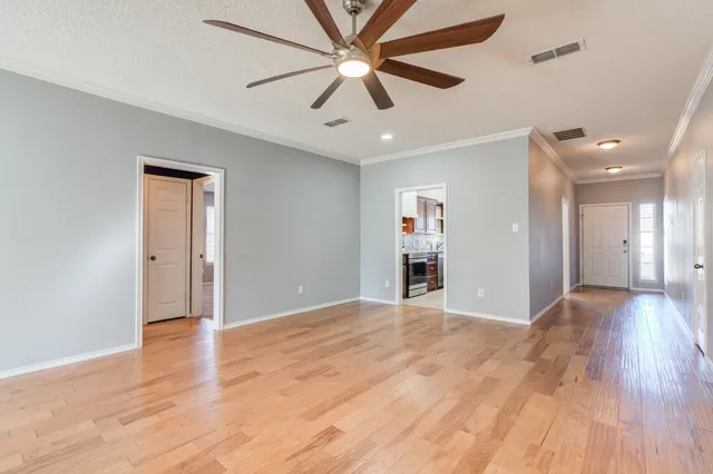 an empty room with wooden floor and a ceiling fan