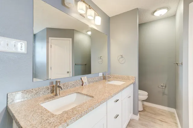 a bathroom with a granite countertop sink a toilet and a mirror