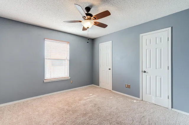 an empty room with windows and ceiling fan