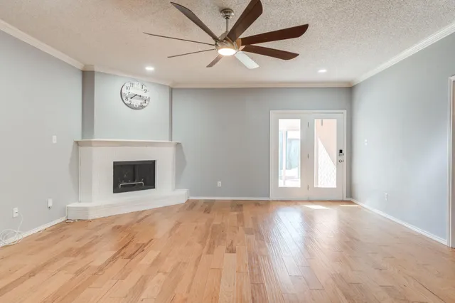 a view of a livingroom with a fireplace a ceiling fan and wooden floor
