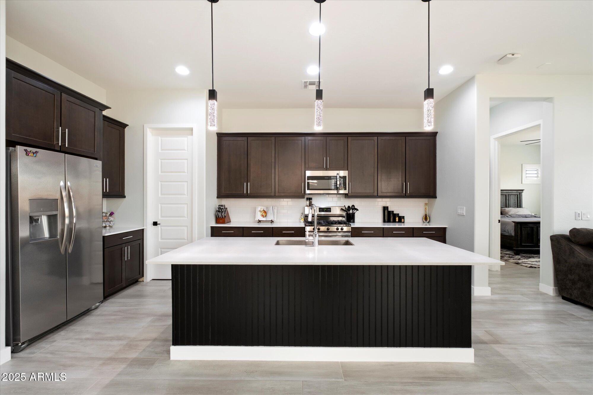 20954 East Camacho Road Queen Creek, AZ 85142 - Photo 3 of 35 a kitchen with stainless steel appliances kitchen island granite countertop a refrigerator a sink a stove a microwave and wooden cabinets