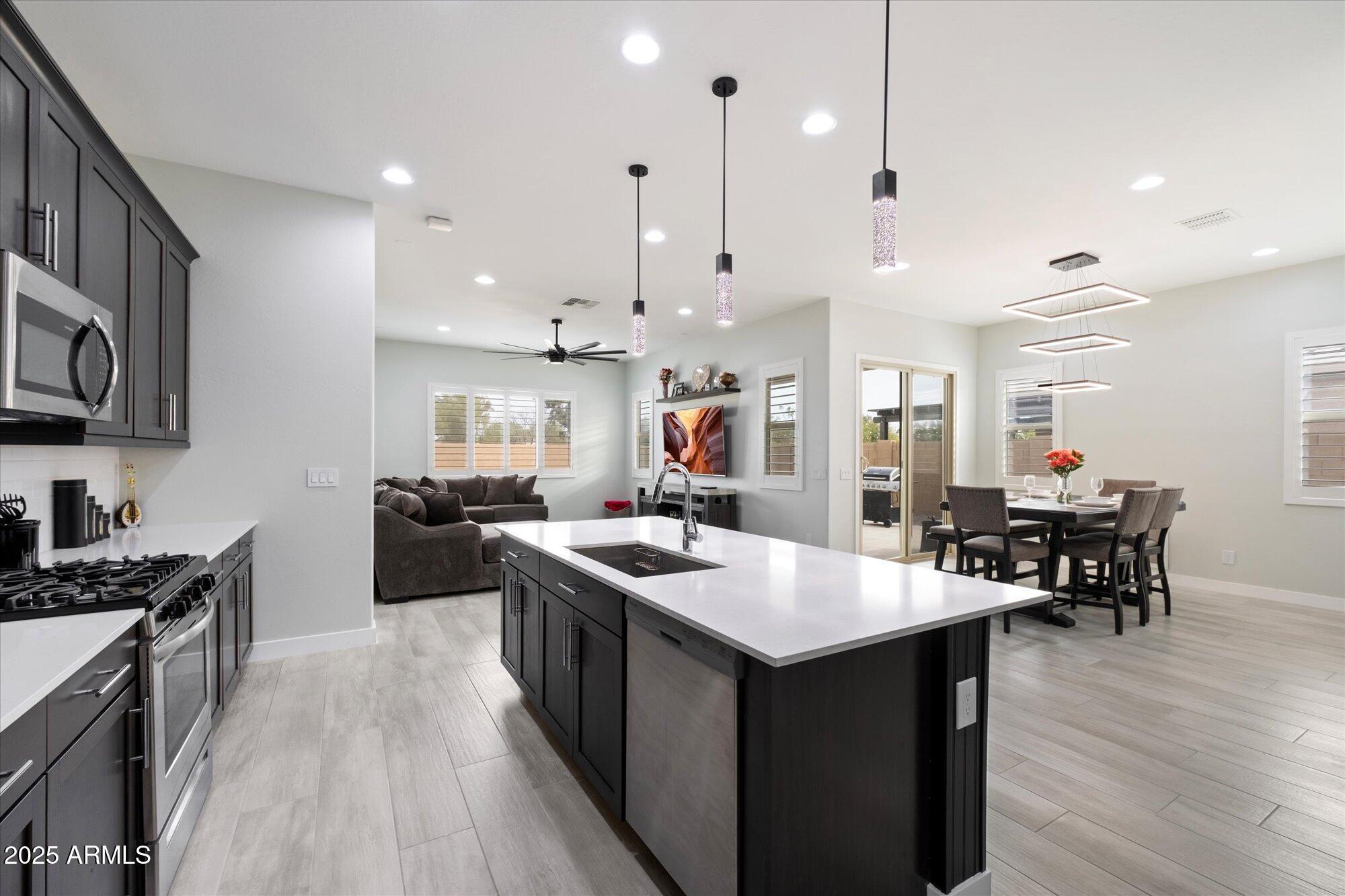 20954 East Camacho Road Queen Creek, AZ 85142 - Photo 4 of 35 a kitchen with stainless steel appliances a stove a sink a kitchen island with wooden floor and chairs