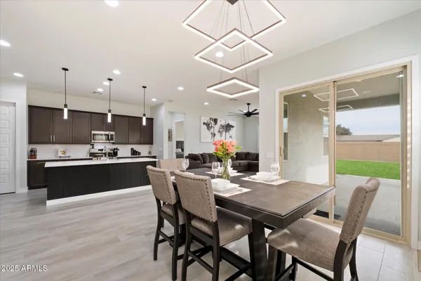 a kitchen with stainless steel appliances kitchen island granite countertop a table chairs refrigerator and microwave