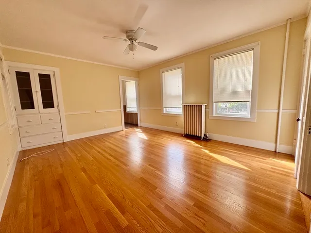 a view of an empty room with a window and wooden floor