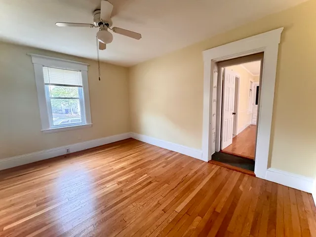 an empty room with wooden floor chandelier fan and windows