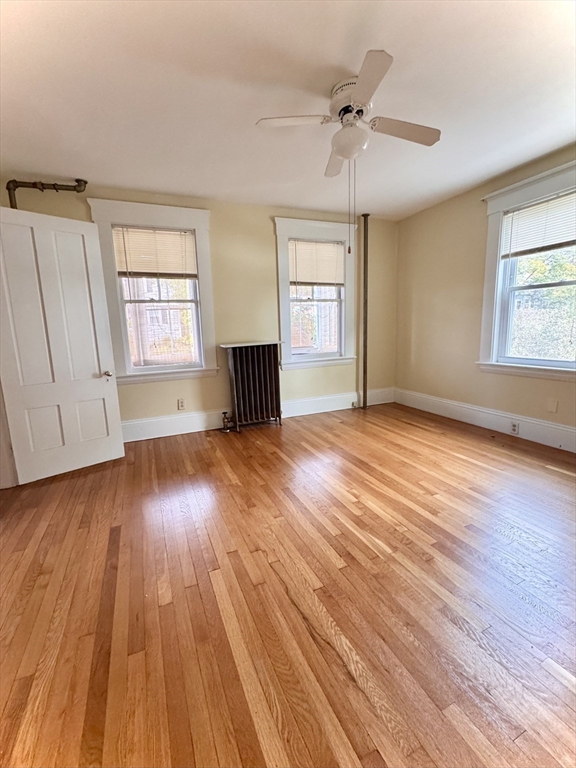 57 Adams Avenue Newton, MA 02465 - Photo 9 of 38 an empty room with wooden floor chandelier fan and windows