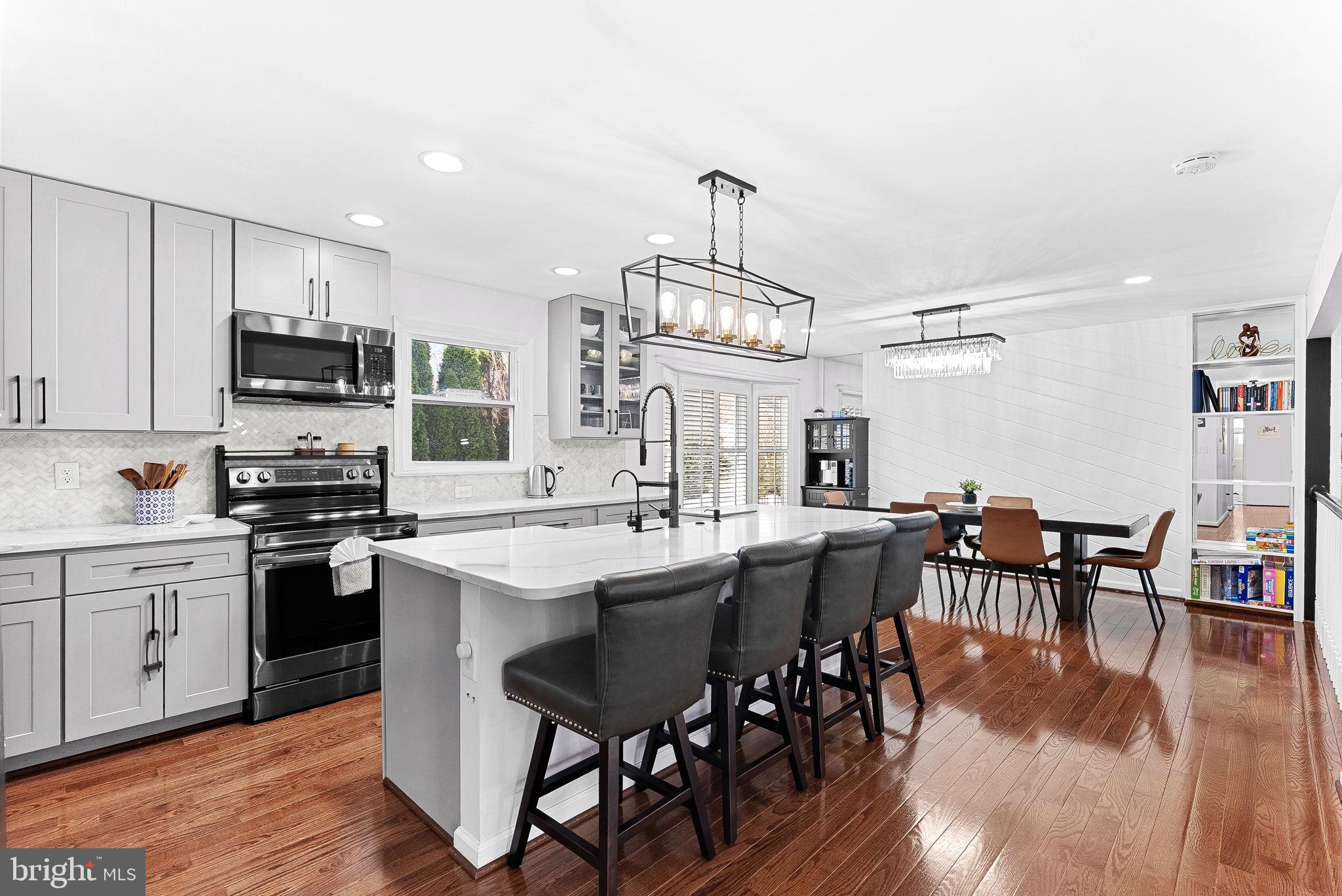 6208 Ormandy Drive Burke, VA 22015 - Photo 9 of 57 a kitchen with stainless steel appliances a kitchen island hardwood floor sink stove dining table and chairs