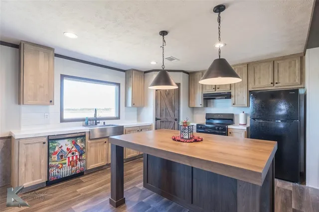 a kitchen with stainless steel appliances a sink a stove a center island and a wooden floor