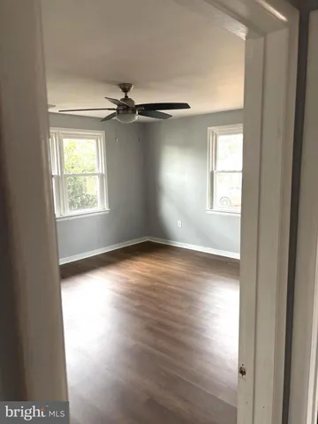 an empty room with wooden floor windows and ceiling fan
