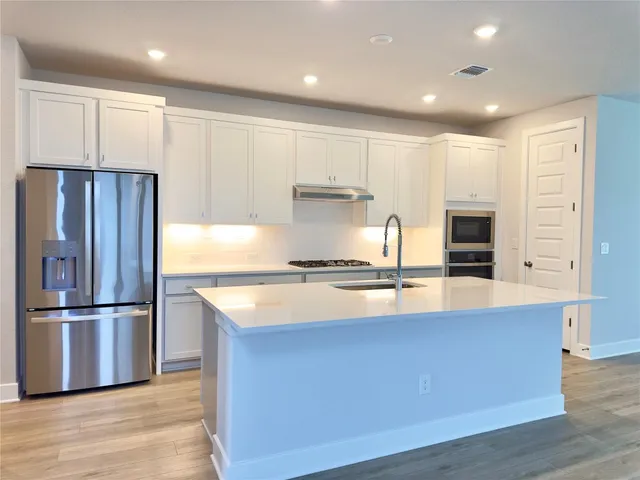 a kitchen with kitchen island a counter top space cabinets and stainless steel appliances