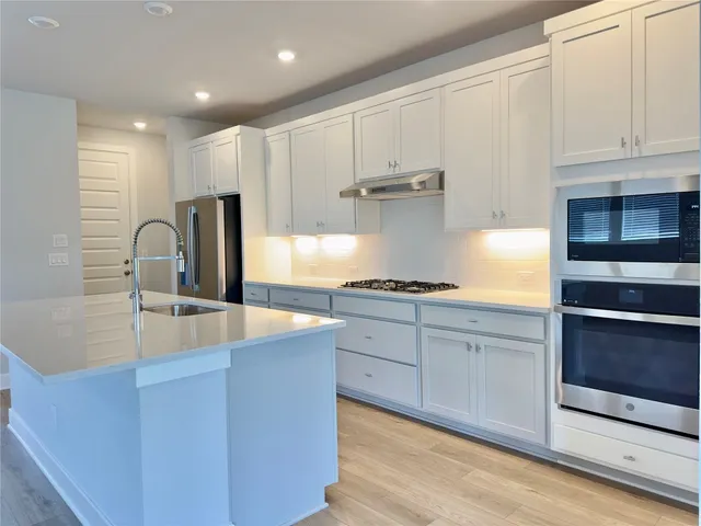 a kitchen with kitchen island granite countertop a sink cabinets and stainless steel appliances