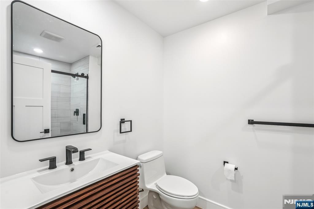 492 Oaktree Road Oradell, NJ 07649 - Photo 38 of 43 a bathroom with a sink a toilet a mirror and vanity