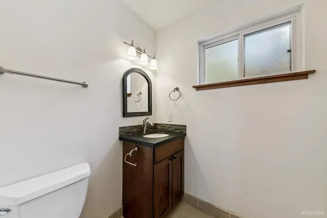 a bathroom with a granite countertop sink a toilet and mirror