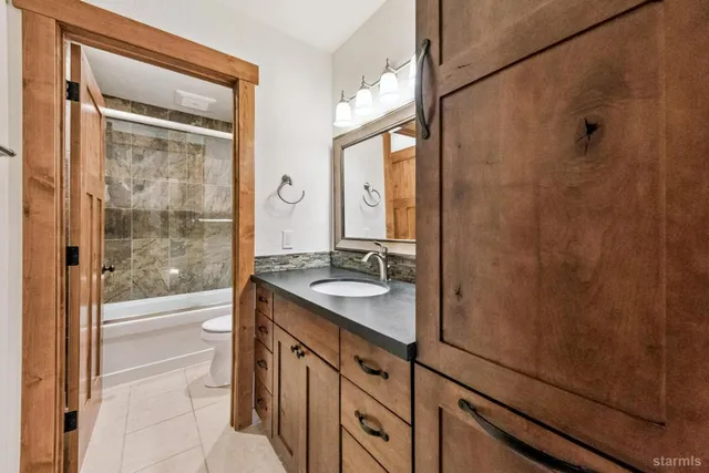a bathroom with a granite countertop sink a mirror and shower