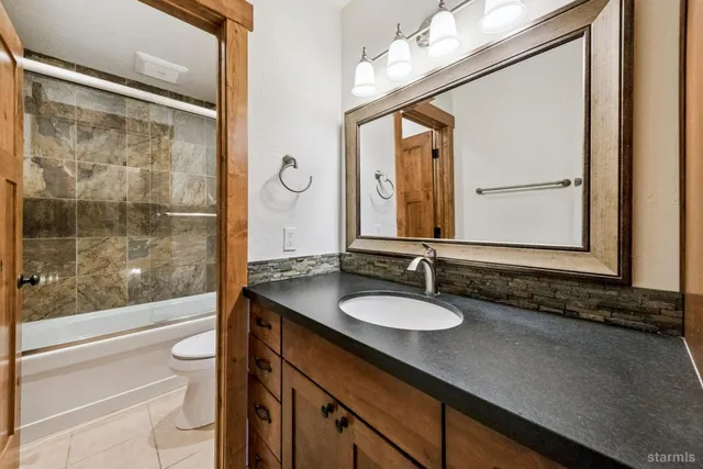 a bathroom with a granite countertop sink mirror vanity and toilet