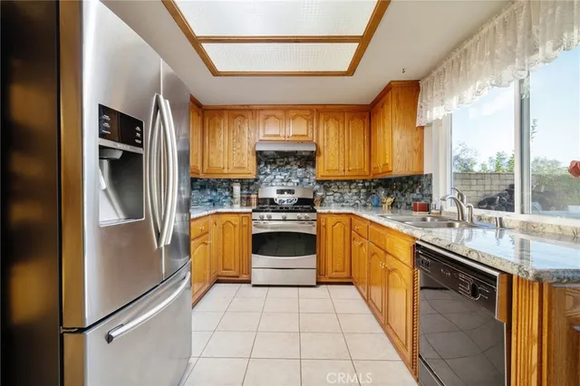 a kitchen with granite countertop cabinets stainless steel appliances a sink and a window