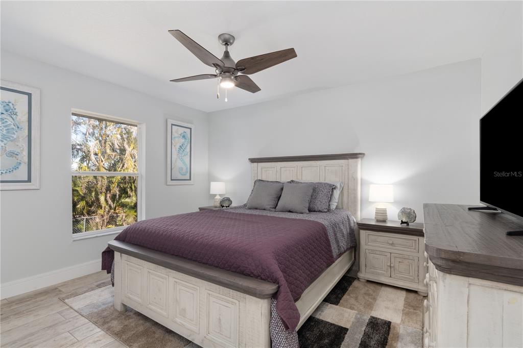193 Beeney Road Southeast Port Charlotte, FL 33952 - Photo 19 of 45 a spacious bedroom with a bed and a flat screen tv
